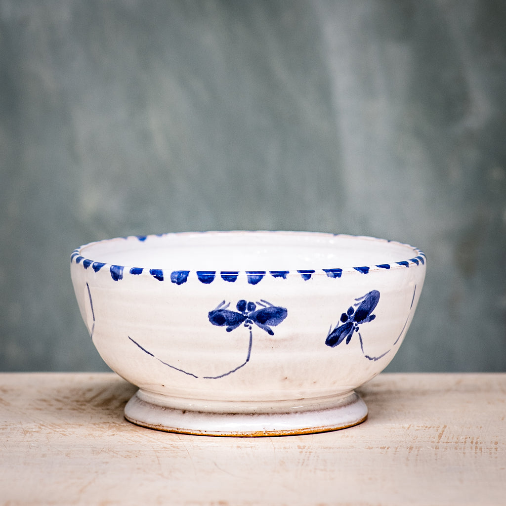 A ceramic cereal bowl with a white base and blue floral pattern on the side, placed against a grey background.