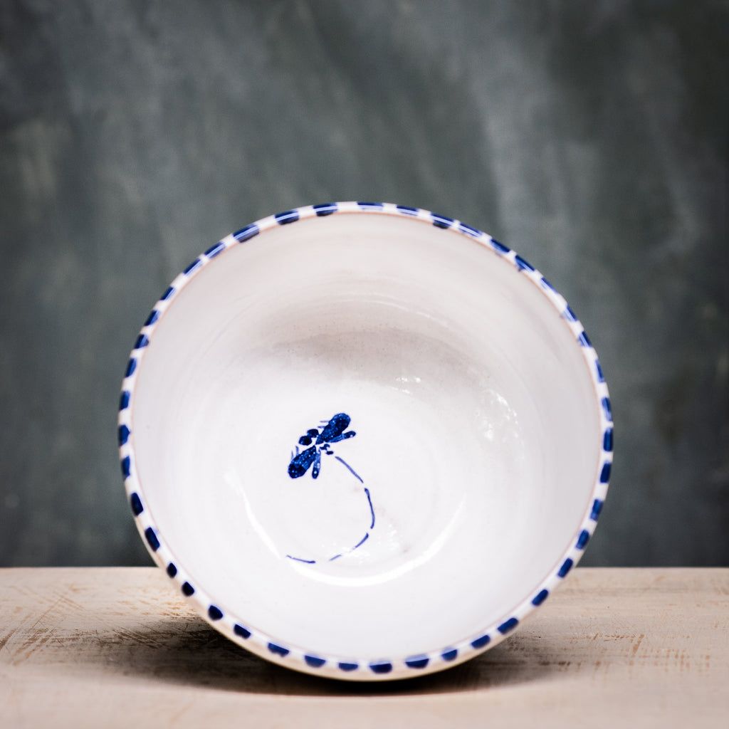 A ceramic cereal bowl with a white base and blue floral pattern on the side, placed against a grey background.