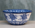 A ceramic salad bowl with blue floral patterns on a white background, displayed against a neutral backdrop.